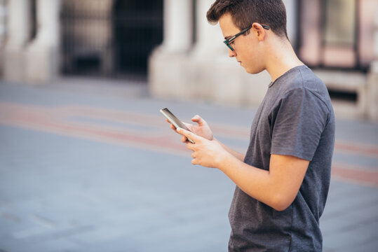 Teenager playing location-based augmented reality game on his smartphone in the city