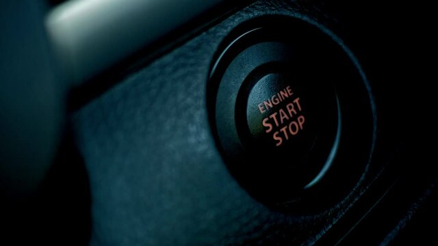 Hand press the button to start stop the car engine, Starting car engine. Close up.