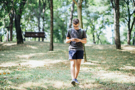 Teenager playing location-based augmented reality game on his smartphone in the city