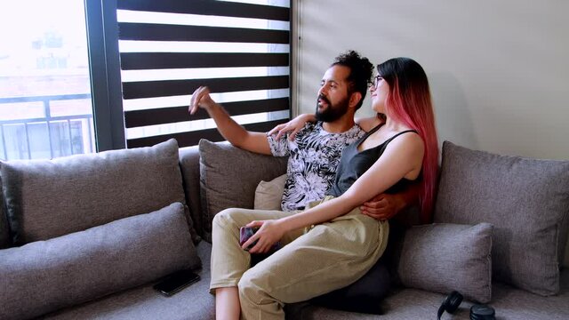 pareja mexicana pasan tiempo juntos en sillon dentro de casa utilizando un telefono inteligente