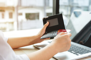 Businesswomen hand take credit cards out of pocket to online shopping on a laptop computer from home for next holidays, payment e-commerce, internet banking, spending money
