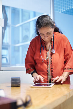 Female doctor at her office using tablet to take notes