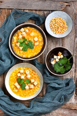 Tasty yellow split pea soup with smoked bacon and toasts on wooden board in rustic style
