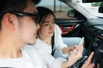 Couple traveler sit inside a car using map application on smartphone.