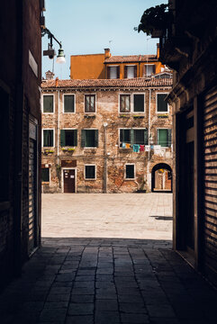Look from dar alley on square and mediterranean style residences on square during sunny day.Italy