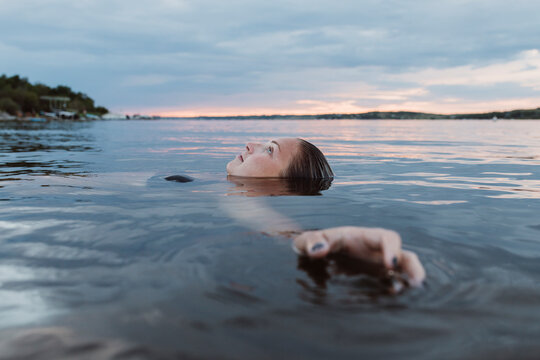 Beautiful woman floating in calm water at sunset