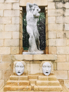 Water fountain with statues of a classical statue of a body and two faces