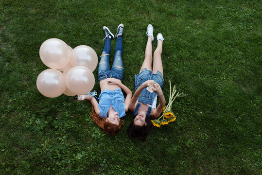 Two best friends laying in the grass taking pictures with their phone