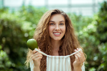 Smiling woman in white shirt holding avocado and smiling