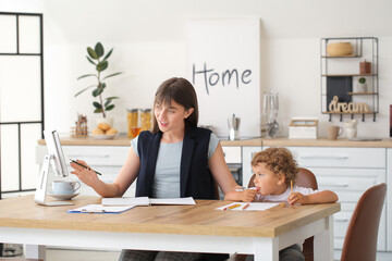 Working mother with little son in kitchen at home