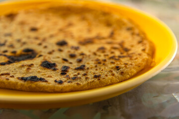 Selective focus view of traditional Indian food Aloo paratha or potato stuffed flat bread over colourful or wooden background. This is popular breakfast dish in north India tourist destination.