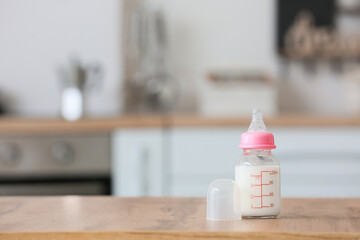 Bottle of milk for baby on table in kitchen