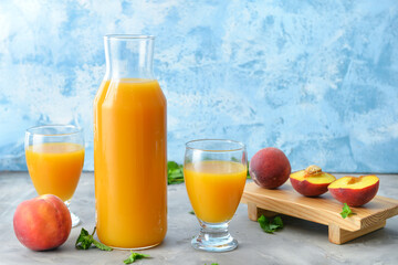 Glasses and bottle of fresh peach juice on table