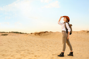 Beautiful fashionable young woman with backpack in desert