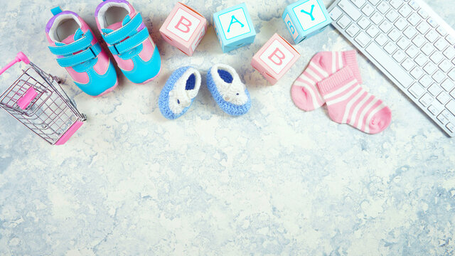 Baby nursery clothing mom bloggers desktop workspace with accessories and shopping cart on white textured background. Top view blog hero header creative composition flat lay. Negative copy space.
