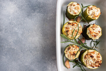 Baked stuffed zucchini columns with minced chicken and vegetables in a ceramic baking dish. copy space