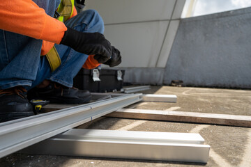 worker wear all safety suit insatlling metal frame on rooftop stock photo