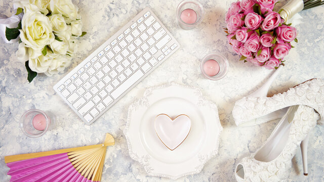 White aesthetic wedding bridal theme desktop workspace with high heel shoes, bouquets and accessories on stylish white textured background. Top view blog hero header creative composition flat lay.