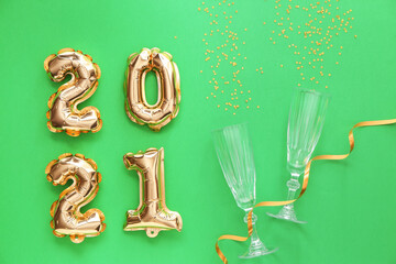 Balloons in shape of figure 2021 and glasses on color background. New Year celebration