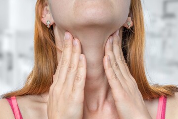 Woman with throat sore is holding her aching throat