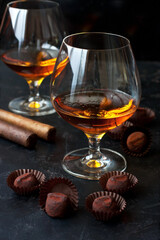 Whiskey or cognac  in  glass with  truffles candy on  dark background