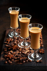 Creamy liqueur in shot glasses on dark background, selective focus