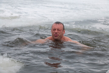 a man in winter in frost extreme swimming at -30, in ice water