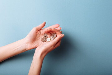 Woman's hands holding a heap of coins background, top view, with copy space