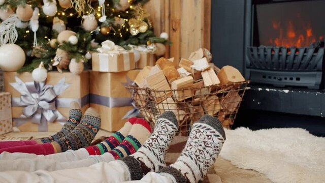 Close-up of feet in cute warm socks indoors in cozy apartment with fireplace and decorated New Year tree. Holidays, interior and people concept.