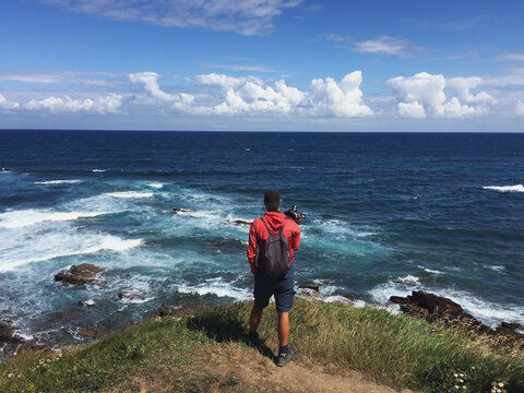 Back View of a lonely hiker looking at the sea