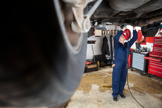 Female Mature Mechanic Using Drill Machine To Repair Car
