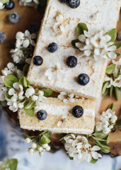 Sweet cake with fresh berries and spring flowers on wood plate,cup of tea, top view 
