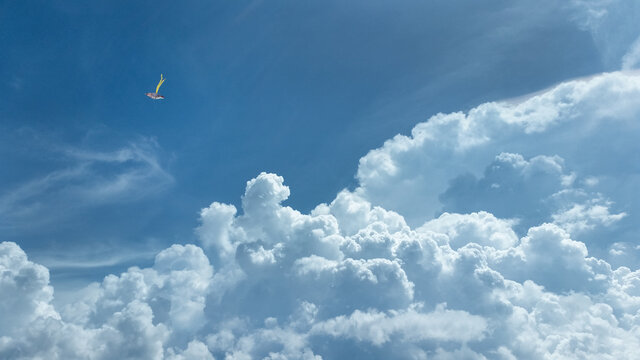 A kite, blue skies, and some majestic cloud formation.