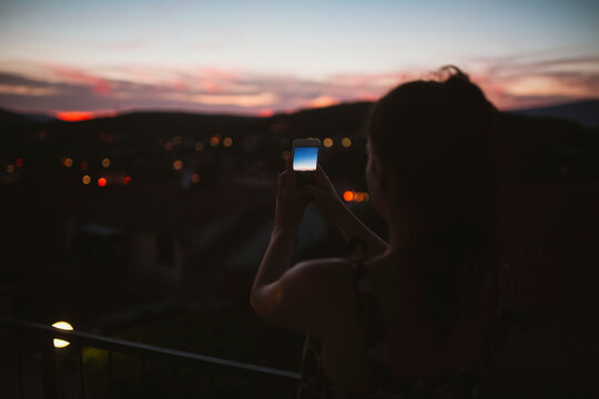 Silhouette of a woman at night taking photos