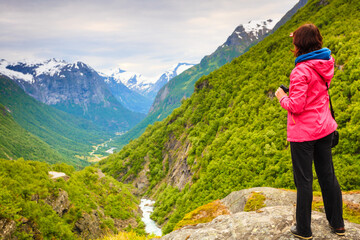 Naklejka na ściany i meble Tourist with camera taking picture in mountains Norway