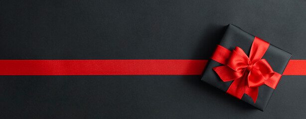 Gift box and red ribbon on black background
