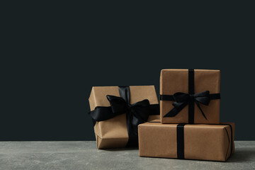 Craft gift boxes with bow on gray table against black background