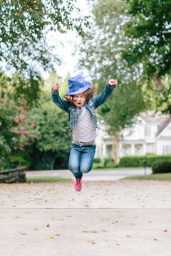Cool young girl wearing a fedora jumping outside