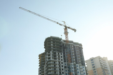 Fototapeta premium High-rise construction with crane against blue sky