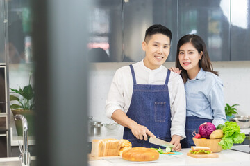 asian man and woman in kitchen, Asian couple chef cooking in kitchen at home, Many foods are put on the table, such as bread vegetables and fruits.