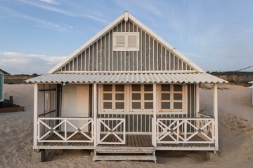 Beautiful characteristic wooden house along the beach side at Costa da Caparica in Lisbon, Portugal. Small village on the beach at sunset facing the Atlantic Ocean, abandoned building on the beach
