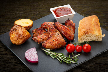 Grilled chicken wings with baked potatoes, matnakash and red sauce. Served on a stone plate