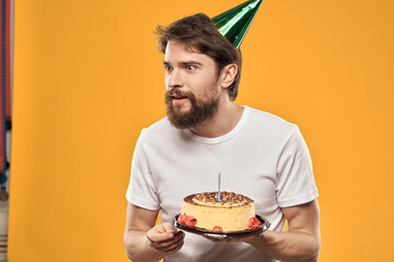 A bearded man with a cake and in a cap celebrating his birthday