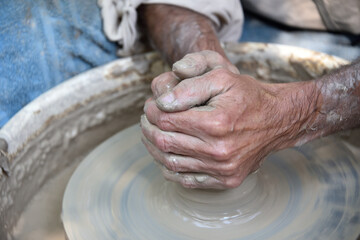 Master potter using a potter's wheel creates a vase from clay