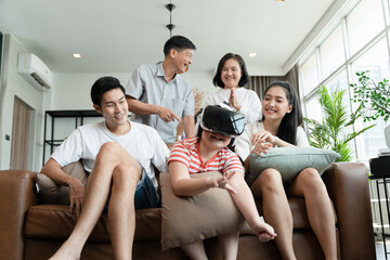 Asian little girl kid play virtual game goggles with parent in the living room during weekend, Happy family spending time together during holiday. 