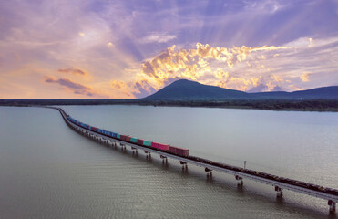 Aerial view, Freight train above the lake of  Pa Sak Jolasid dam at Lopburi unseen Thailand  during beautiful sunset. Amazing Thailand Train run on the bridge look like floating on the water.