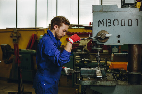 portrait of a metal worker drilling some metal at a drilling machine