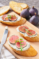 Bruschetta with ricotta cheese, ripe figs and honey served on a small cutting board. Top view.