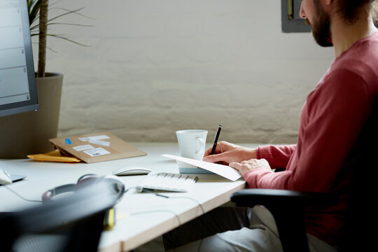 Creative Businessman Writing In Book At Desk