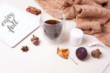 Glass of coffee, knitted beige sweater, tablet, autumn decor and lettering enjoy fall on a white background